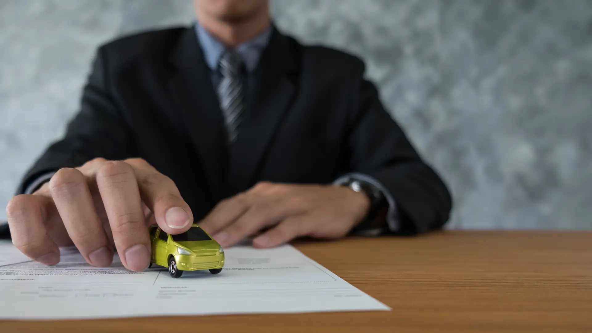 car insurance agent holding toy car on document